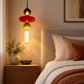 Colourful stacked glass pendant displayed beside a bed in a warm modern interior