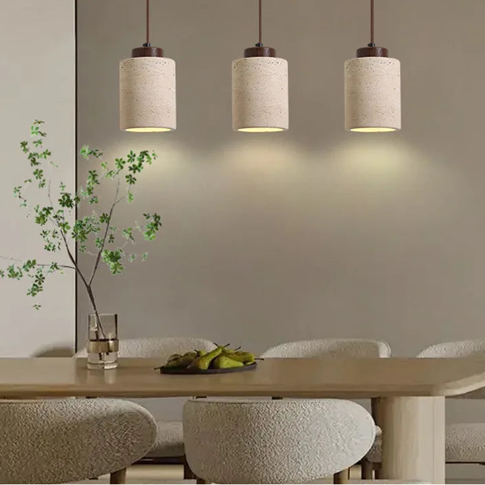Three textured cylinder pendants arranged above a dining table.