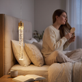 Gold crystal-effect bubble tube pendant light beside a bed