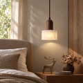Walnut and marble pendant light installed beside a bed