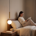 Gold opal glass globe pendant light above a bedside table in a calm bedroom