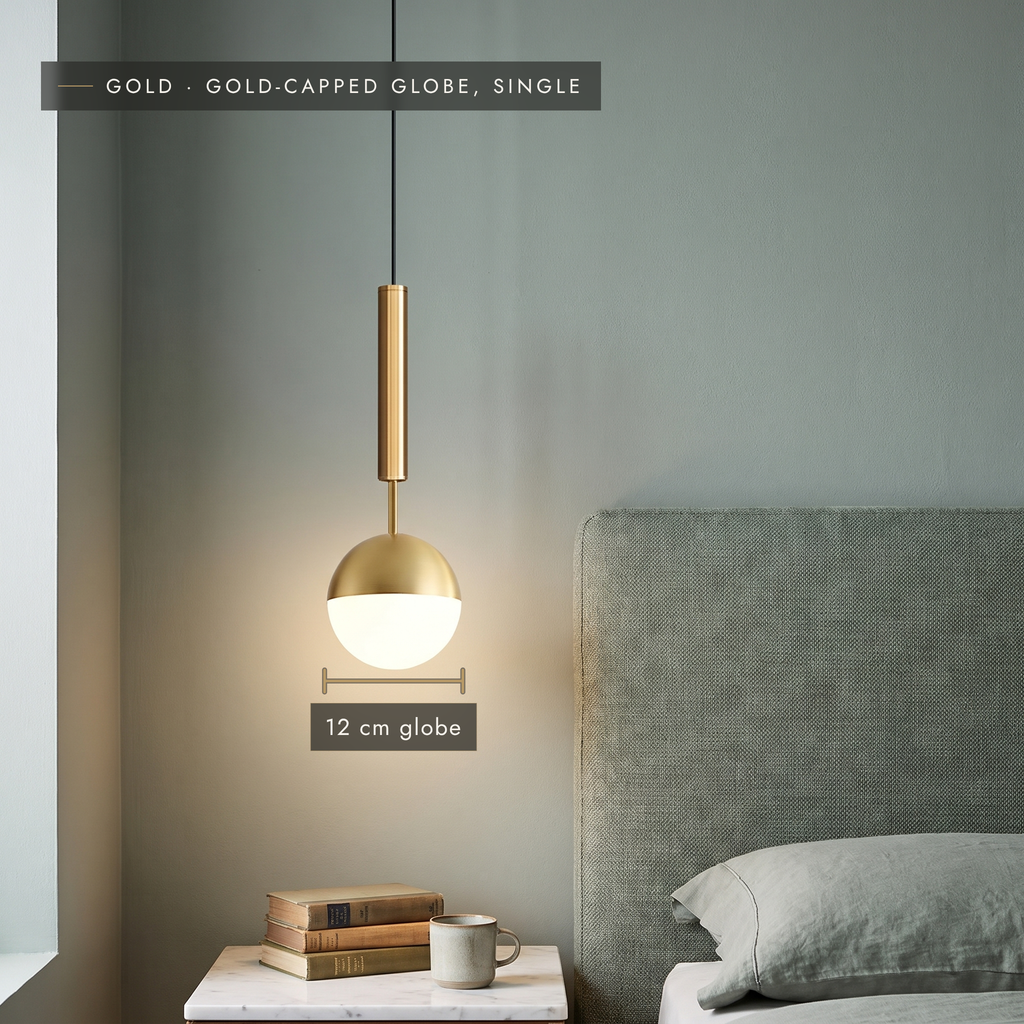 Gold-capped globe pendant light, 12 cm, hanging beside a bed