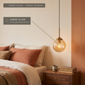 Amber glass globe pendant light beside a bed