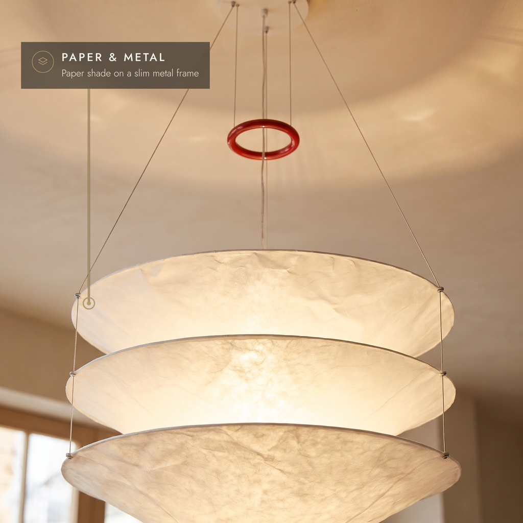 Close-up of the layered paper tiers and red suspension ring, glowing warm white