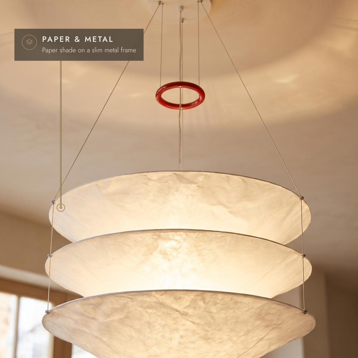 Close-up of the layered paper tiers and red suspension ring, glowing warm white