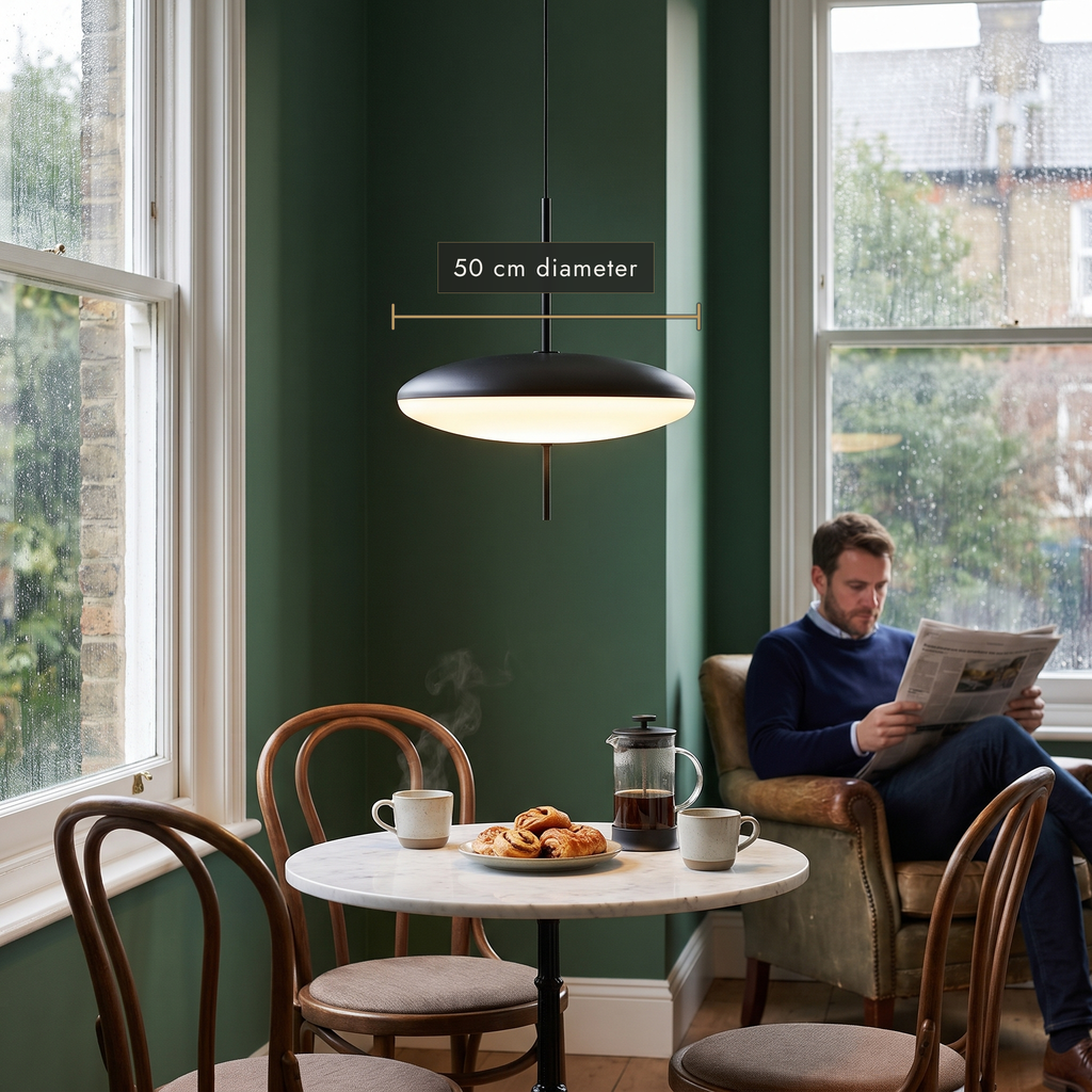 Black and white disc pendant above a marble bistro table in a green dining nook