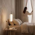 Single ribbed LED pendant with copper finish hanging beside a bed