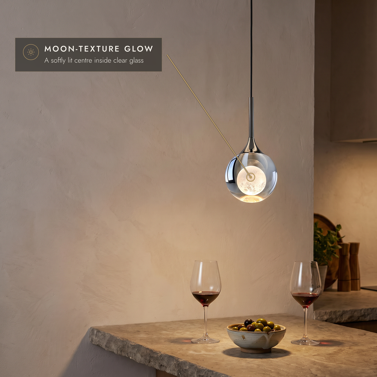 Teardrop pendant light with moon-texture glow above a kitchen worktop